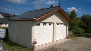 Garage double en béton, couverture ardoises. Deux portes de garage, une porte de service et une fenêtre.