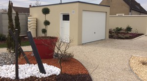 Garage en béton aspect terrasse, couverture bacs acier. Une porte basculante et un porte PVC vitrée.