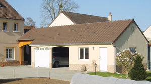 garage en béton 2 pentes couverture tuiles 2 portes sectionnelles avec entrée et fenêtre pvc en façade et auvent accolé