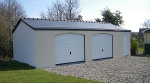 Garage double en béton avec 2 portes sectionnelles et une porte de service en PVC. Couverture en ardoises.